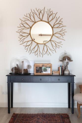a mirror on top of a black console table in a room at Nest Stay By The Butler Collection in Pulborough