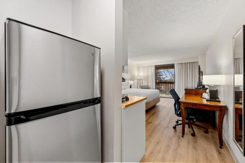 a room with a desk and a refrigerator and a bedroom at Delta Hotels by Marriott Mount Pleasant in Racine