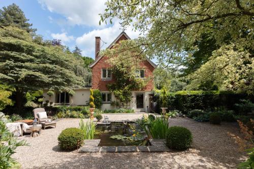 a brick house with a garden and a pond at Nest Stay By The Butler Collection in Pulborough