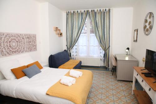 a bedroom with a bed and a desk and a television at Le Mosaïque, proche gare, terrasse, parking privé in Laval