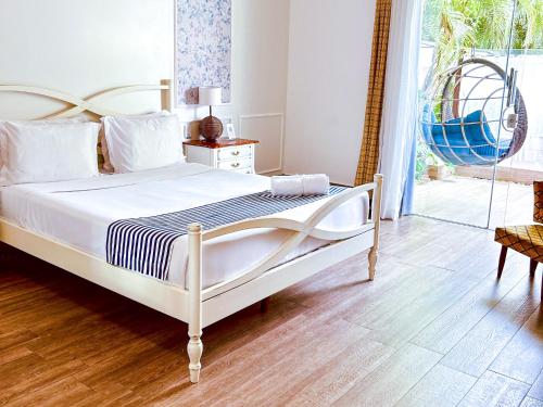 a white bed in a bedroom with a wooden floor at Hotel Boutique Recanto da Passagem in Cabo Frio