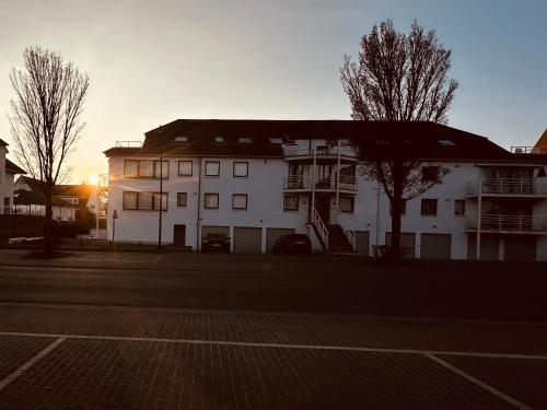 a white building with the sun setting behind it at Studio Lejeune in Koksijde