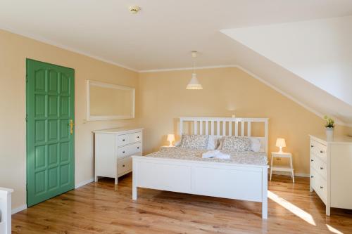 a bedroom with a white bed and a green door at Turciansky dvor in Martin