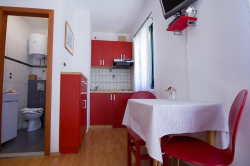 a small kitchen with a table and red cabinets at Apartments Petrinic Crnogaj in Baška
