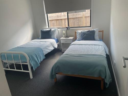 a room with two beds and a window at New Spacious 4 Bedroom Retreat fully air conditioned in Loganholme in Loganholme