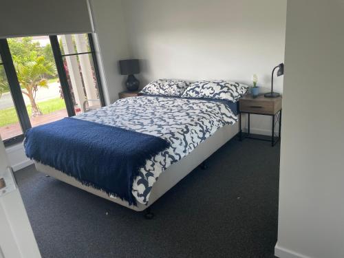 a bedroom with a bed with a blue blanket and a window at New Spacious 4 Bedroom Retreat fully air conditioned in Loganholme in Loganholme