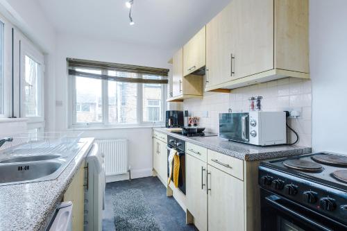 a kitchen with a sink and a stove at Charming 2 Bed House, Sleeps 6, Free parking, Contractors welcome in Elland