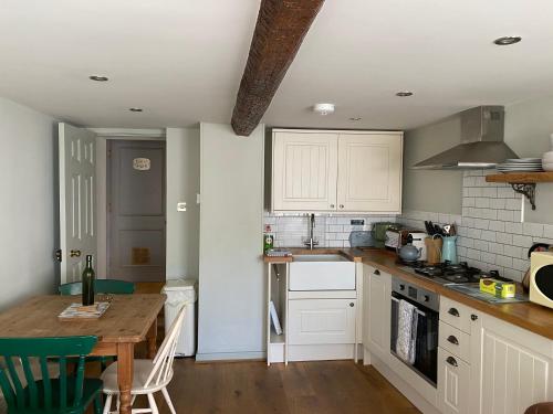 a kitchen with white cabinets and a wooden table at Monmouth House Apartments, Lyme Regis Old Town, dog friendly in Lyme Regis