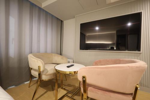 a room with two chairs and a table and a tv at Masan Den Basta Gyeongnam Uni in Changwon