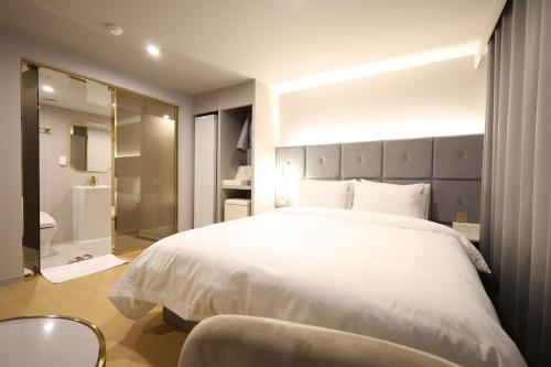 a bedroom with a large white bed and a bathroom at Masan Den Basta Gyeongnam Uni in Changwon