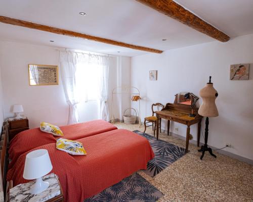 - une chambre avec un lit rouge et un bureau dans l'établissement L'Escarpolette, à Saint-Saturnin-lès-Apt