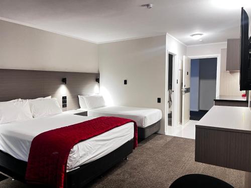 a hotel room with two beds and a kitchen at Manukau Hotel & Conference Centre in Auckland