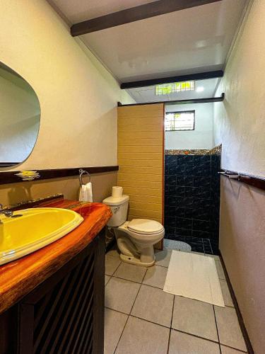 a bathroom with a yellow sink and a toilet at Cabinas Ole Caribe in Puerto Viejo
