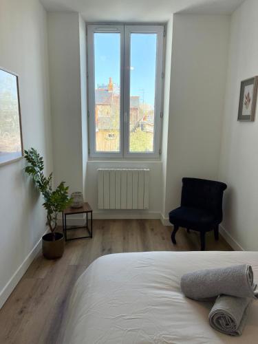 a bedroom with a bed and a chair and a window at Le Breizh -T2 en centre ville in Rennes
