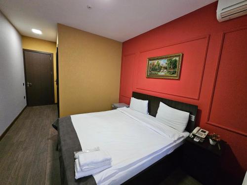 a bedroom with a large bed with a red wall at Aden City Hotel in Baku