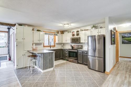 a kitchen with white cabinets and a stainless steel refrigerator at 11 Mi to Bozeman Family Home with Movie Room! in Belgrade