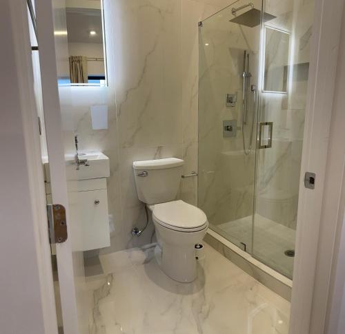 a white bathroom with a toilet and a shower at Modern, New 3 bed, 2 bath Apt near Manhattan in Jersey City