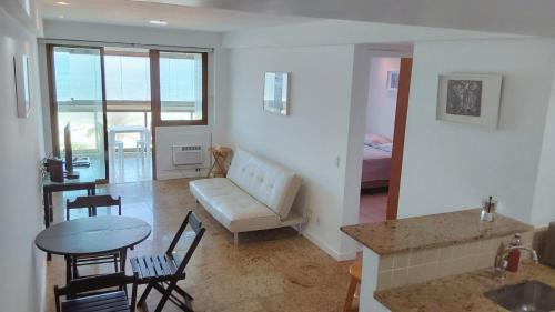una sala de estar con un sofá, una mesa y sillas en Flat Residencial Praia da Barra, Piscina e Sauna - Frente Mar D68508, en Río de Janeiro