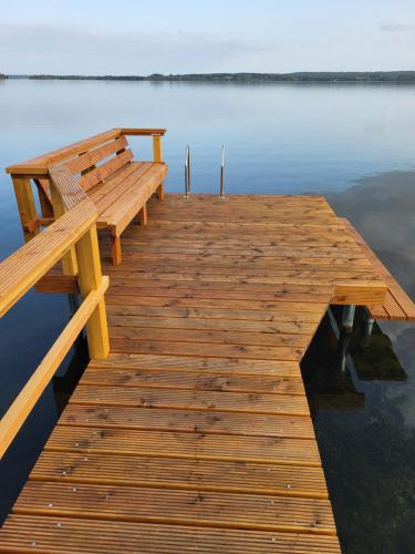 a wooden dock with a bench sitting on the water at FerienWohnung SeeUfer am Plöner See in Ascheberg
