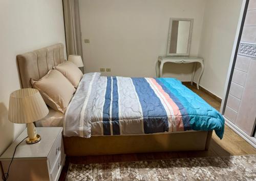 a bedroom with a bed and a table with a lamp at ALEX HOMES - Gleem Luxury Apartments with Direct Sea View in Alexandria