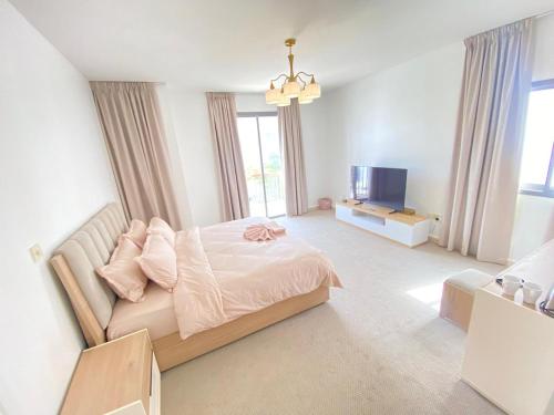 a white bedroom with a bed and a television at Dinar - villa master bedroom in Abu Dhabi