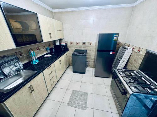 a small kitchen with a sink and a refrigerator at ALEX HOMES - Gleem Luxury Apartments with Direct Sea View in Alexandria
