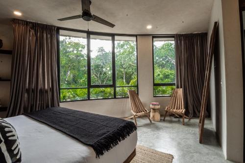 a bedroom with a bed and two chairs and windows at Tulum Jungle Luxury Villa Priv pool & Concierge 4B in Tulum