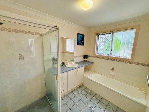 un bagno con doccia, lavandino e vasca di Waratah Retreat a Evans Head