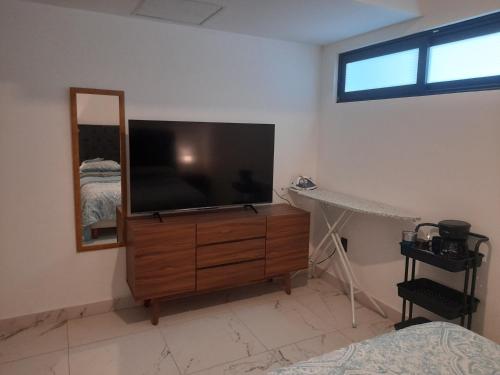 a bedroom with a tv and a dresser with a mirror at Departamento con Gran Vista in Monterrey