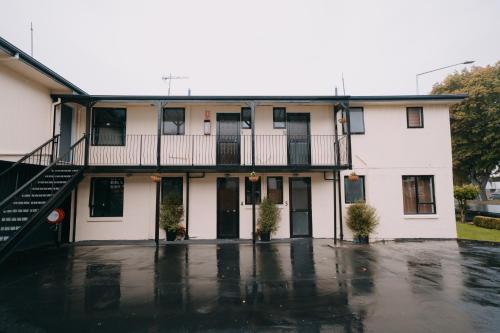 a white house with a balcony and a parking lot at 301 Bealey Ave Motel Very Close to City Centre and Hagley park in Christchurch