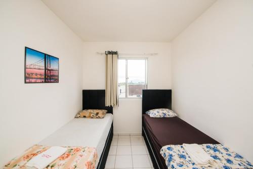 Dos camas en una habitación con ventana. en Apartamento próximo a BR 101 ideal para viajantes, en Palhoça