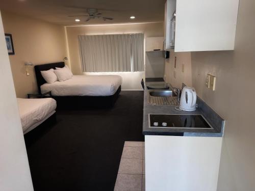 a small kitchen with two beds and a sink in a room at Albany Executive Motor Inn Limited in Auckland