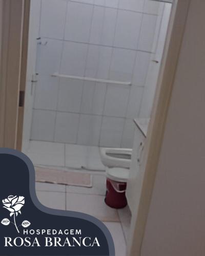 a bathroom with a toilet and a white tiled wall at Hospedagem Rosa Branca in Uberlândia