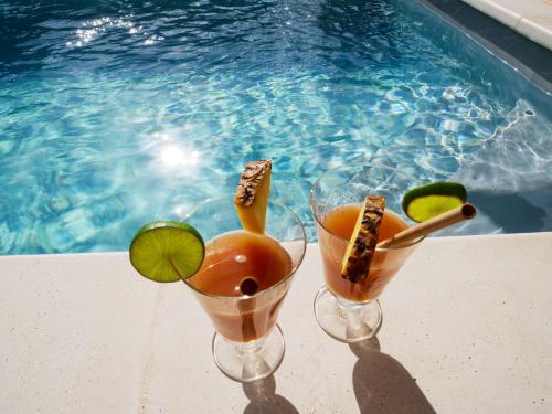 two cocktails in wine glasses next to a swimming pool at Coco Soley in Le Diamant