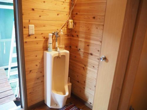 a bathroom with a urinal in a wooden wall at 奄美大島 龍郷町 体験の宿 こうりゅう館 in Tatsugo
