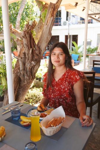 a woman sitting at a table with food at Maamadi Boutique in Maafushi