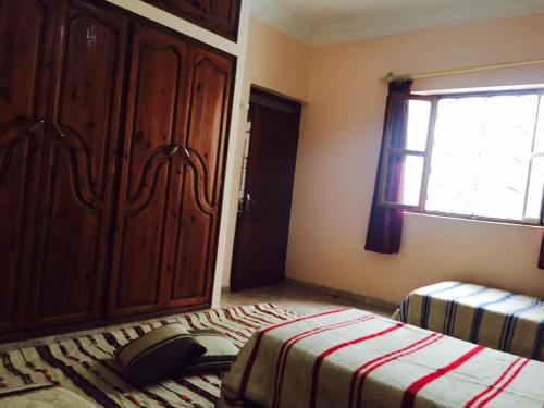 a bedroom with a bed and a cabinet and a window at Chez Fouzia in Essaouira