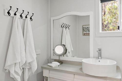 a white bathroom with a sink and a mirror at Bulga Amaroo in Bilpin