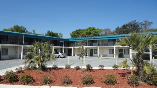 an exterior view of a building with palm trees at Western Inn - Pensacola in Pensacola