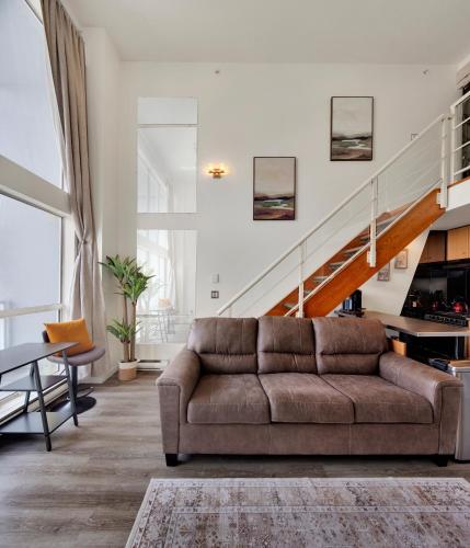 a living room with a couch and a staircase at Two-Story Loft with a High-rises view and Rooftop Deck in Vancouver