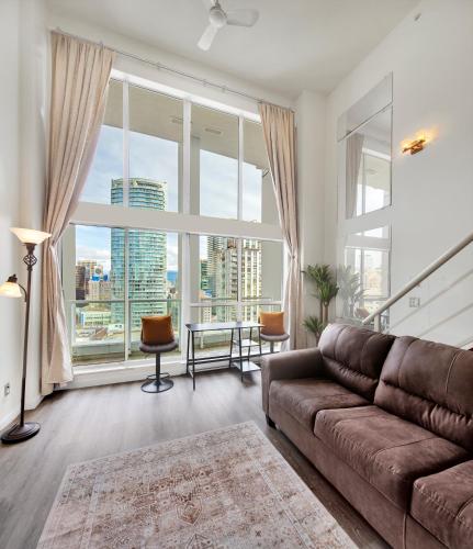 a living room with a couch and a large window at Two-Story Loft with a High-rises view and Rooftop Deck in Vancouver