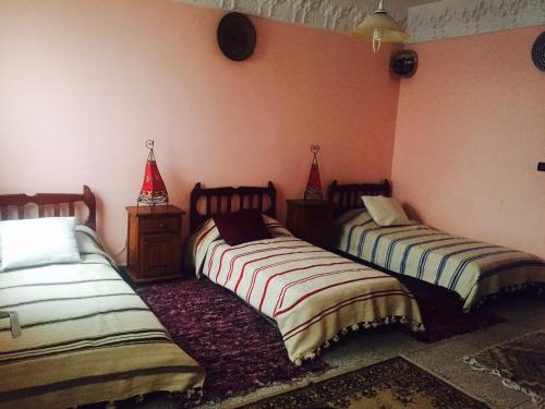 two beds in a room with pink walls at Chez Fouzia in Essaouira