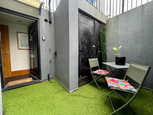 a patio with green grass and two chairs and a table at Modern Central Large Studio Sleeps 4 in Brighton & Hove