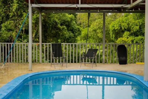 a swimming pool with two chairs and a cat reflection in the water at Puravidovo, ocean view, hill side in Golfito