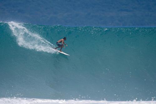 a man riding a wave on a surfboard in the ocean at Puravidovo, ocean view, hill side in Golfito