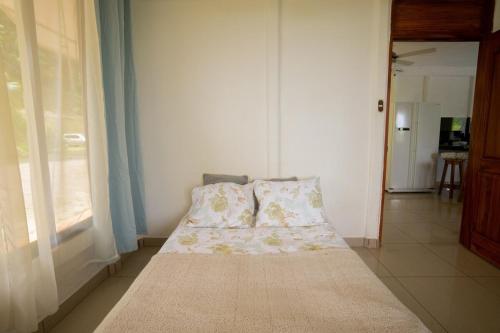 a small bed in a room with a window at Puravidovo, ocean view, hill side in Golfito