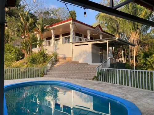 a house with a swimming pool in front of it at Puravidovo, ocean view, hill side in Golfito