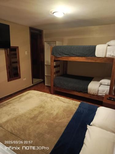 a room with two bunk beds and a rug at Hotel Guajacum Riobamba in Riobamba