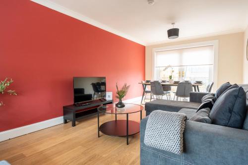 a living room with a couch and a tv at Beauly Court Suites in Grangemouth