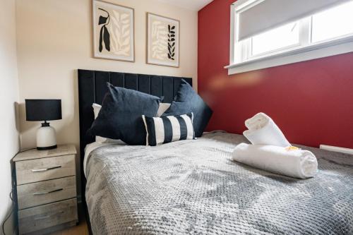 a bedroom with a bed with a black headboard and a window at Beauly Court Suites in Grangemouth